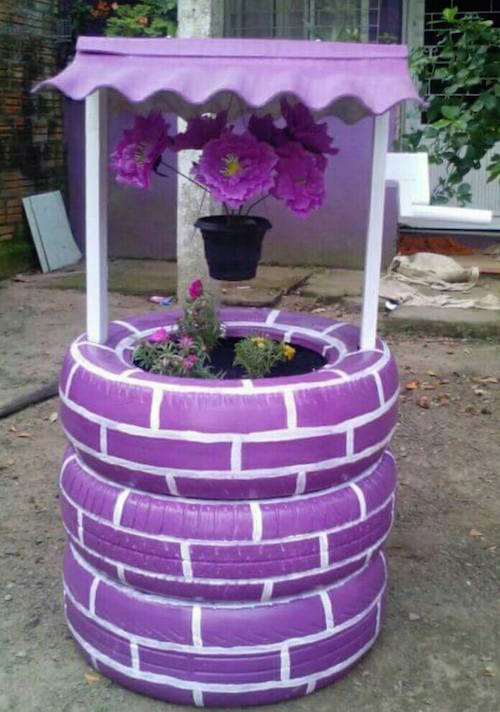 Wow - this is made from recycled and painted tires! Just stack them, drill some holes, and nail a roof on. Love those hanging flowers!