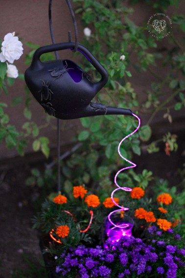 Halloween Watering Can with Lights. Spooky creepy crawlers on a black watering can with cascading purple lights.