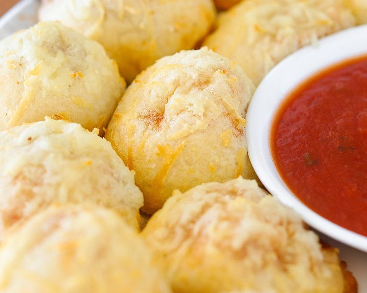 Homemade Pizza Poppers are filled with melted mozzarella cheese and mini pepperoni and then topped with an irresistible cheesy, garlic, butter glaze. Dipped in additional pizza sauce or ranch dressing, these are simply addicting! They are a fun, kid-friendly, finger food recipe for lunch, an after-school snack, or your next party! 