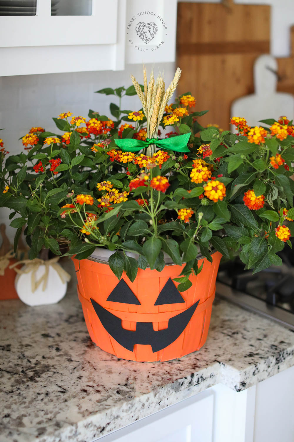 DIY Halloween Pumpkin Planter with orange flowers and glowing lights! How to make a Jack-O-Lantern planter basket with this fall craft idea!