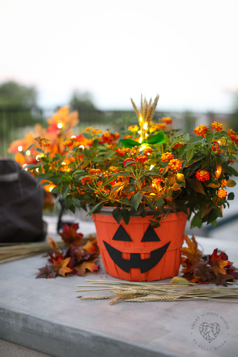 DIY Halloween Pumpkin Planter with orange flowers and glowing lights! How to make a Jack-O-Lantern planter basket with this fall craft idea!