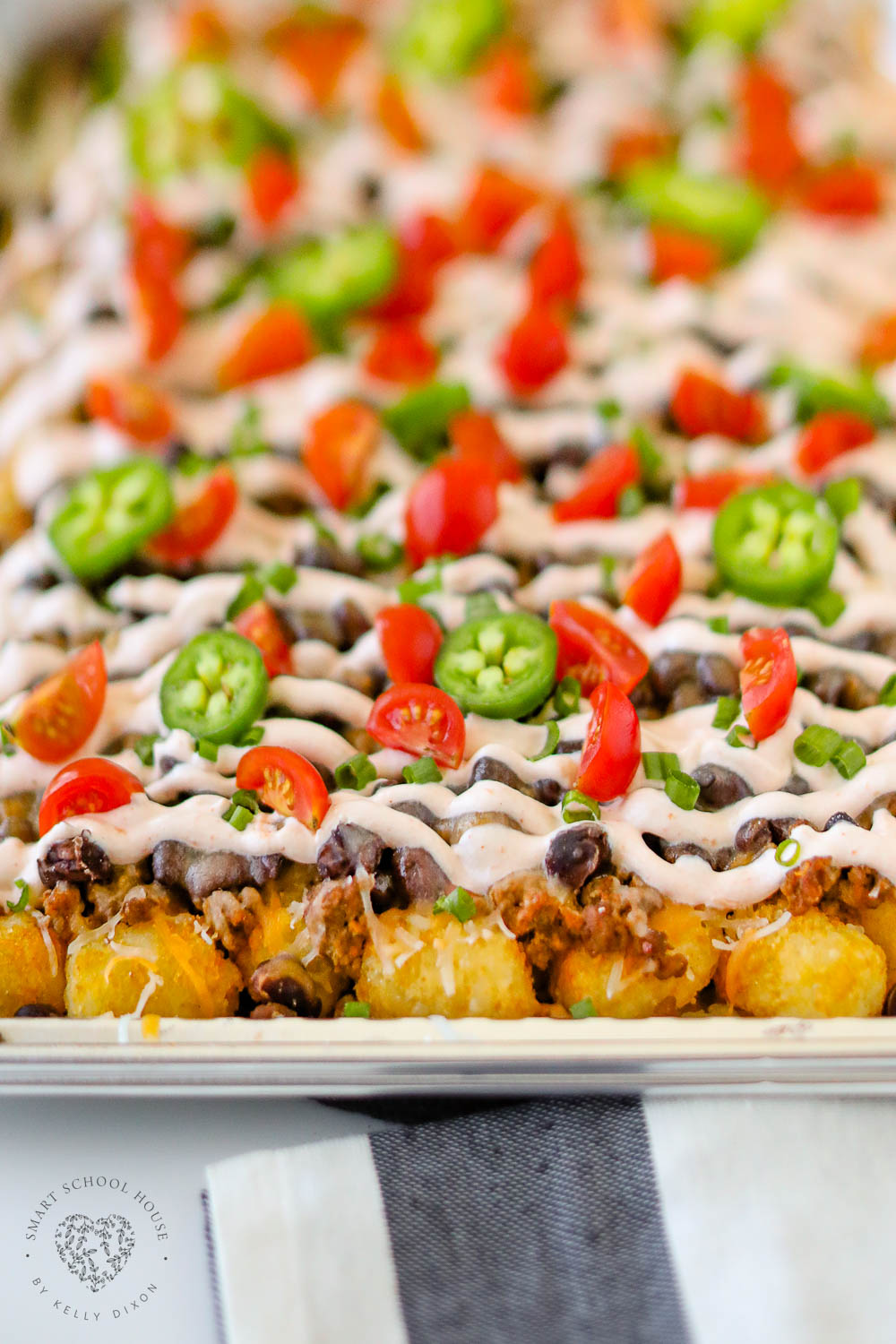 Creamy cheesy Tatchos recipe! Tater tot nachos are layered meat, cheese, and a delicious creamy drizzle!