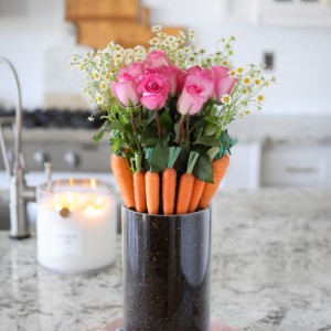 A pretty Carrot Patch Bouquet for Easter and spring! Fresh flowers sit inside of a hidden vase surrounded by carrots nestled in soil.